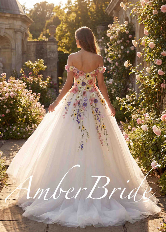 A-line off-shoulder wedding dress with colorful floral embroidery on white tulle in a garden setting.