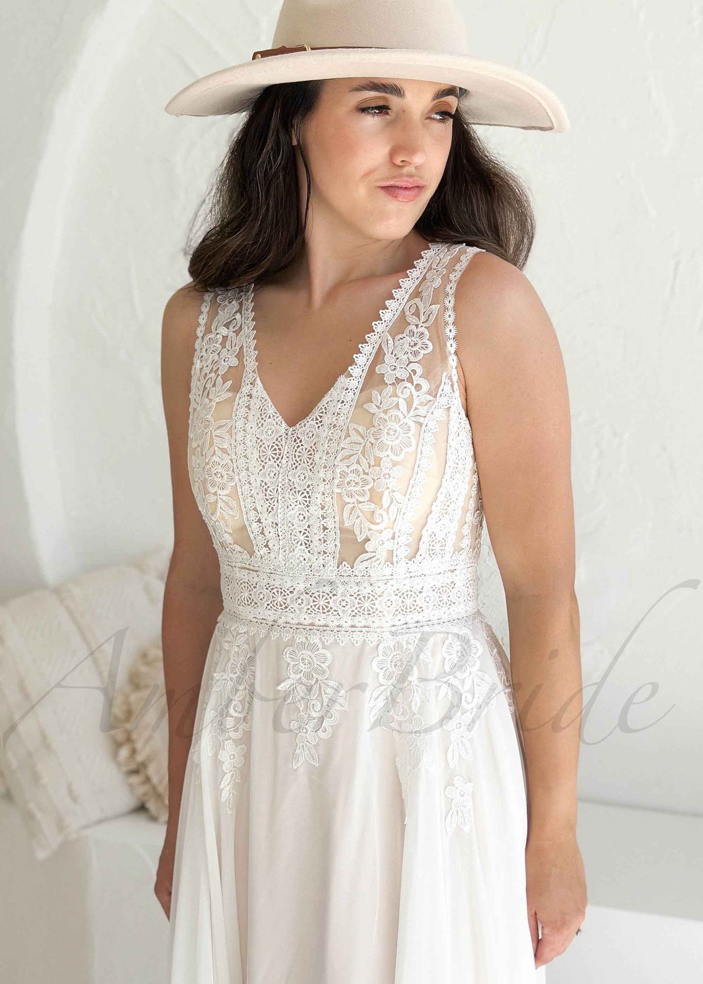 Woman wearing a white lace dress and beige hat against a white background