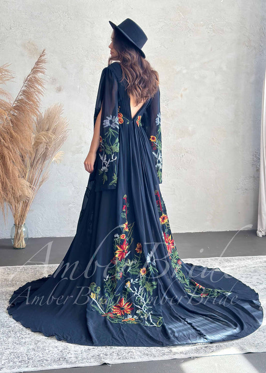 Black A-line bridal gown with flowing sleeves, V-back, and vibrant multi-colored floral embroidery on skirt and arms.