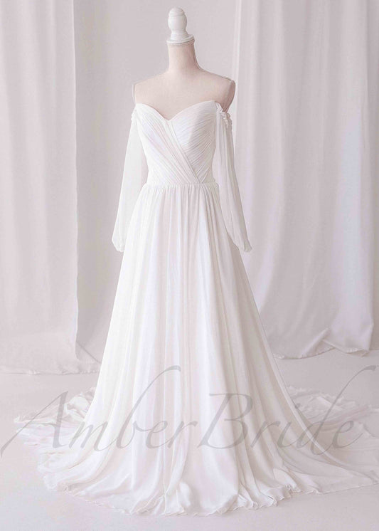 Off-shoulder A-line wedding dress in white chiffon with pleated bodice and long sheer sleeves on a mannequin.