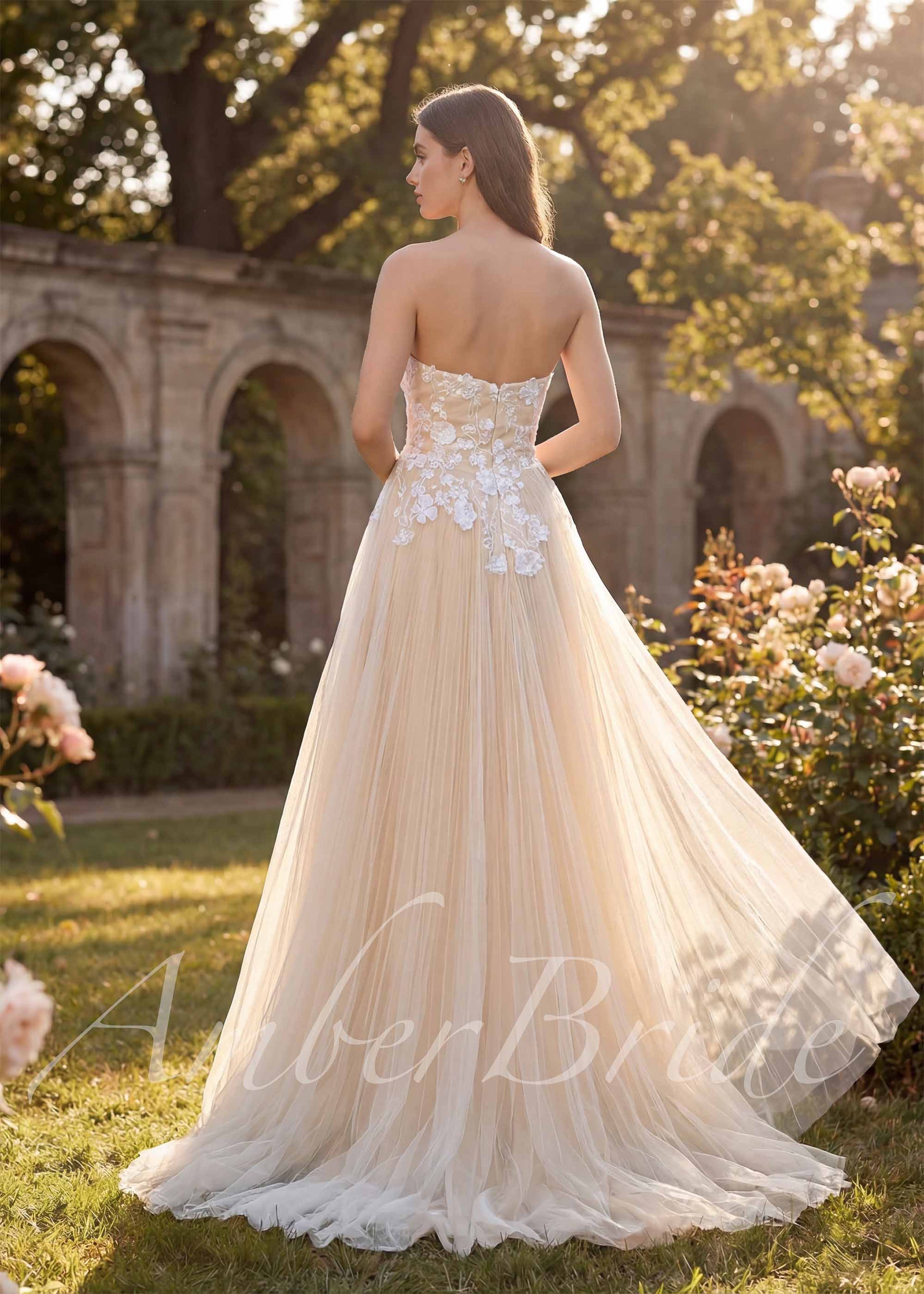 Back view of a strapless A-line wedding dress with a champagne tulle skirt and white floral lace bodice appliqués.