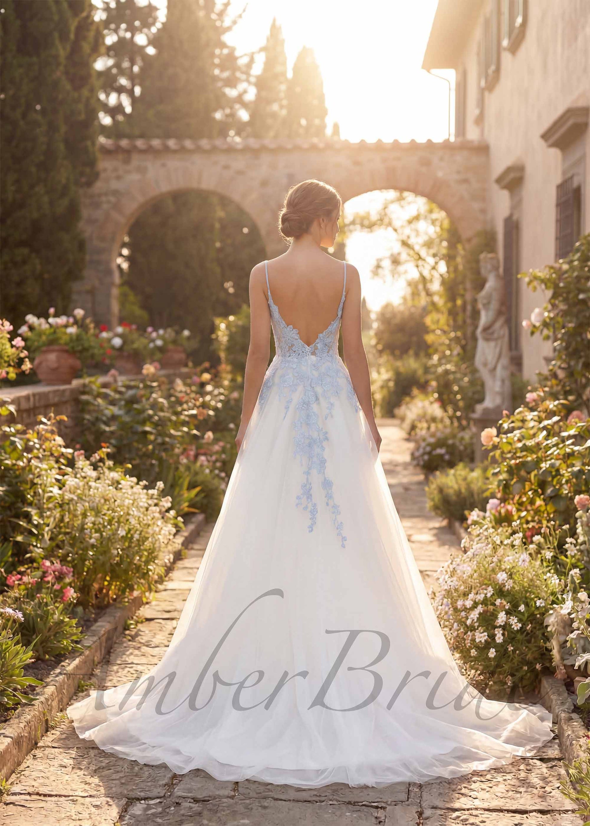 Back view of a white A-line tulle wedding dress with light blue floral embroidery, spaghetti straps, and open back.