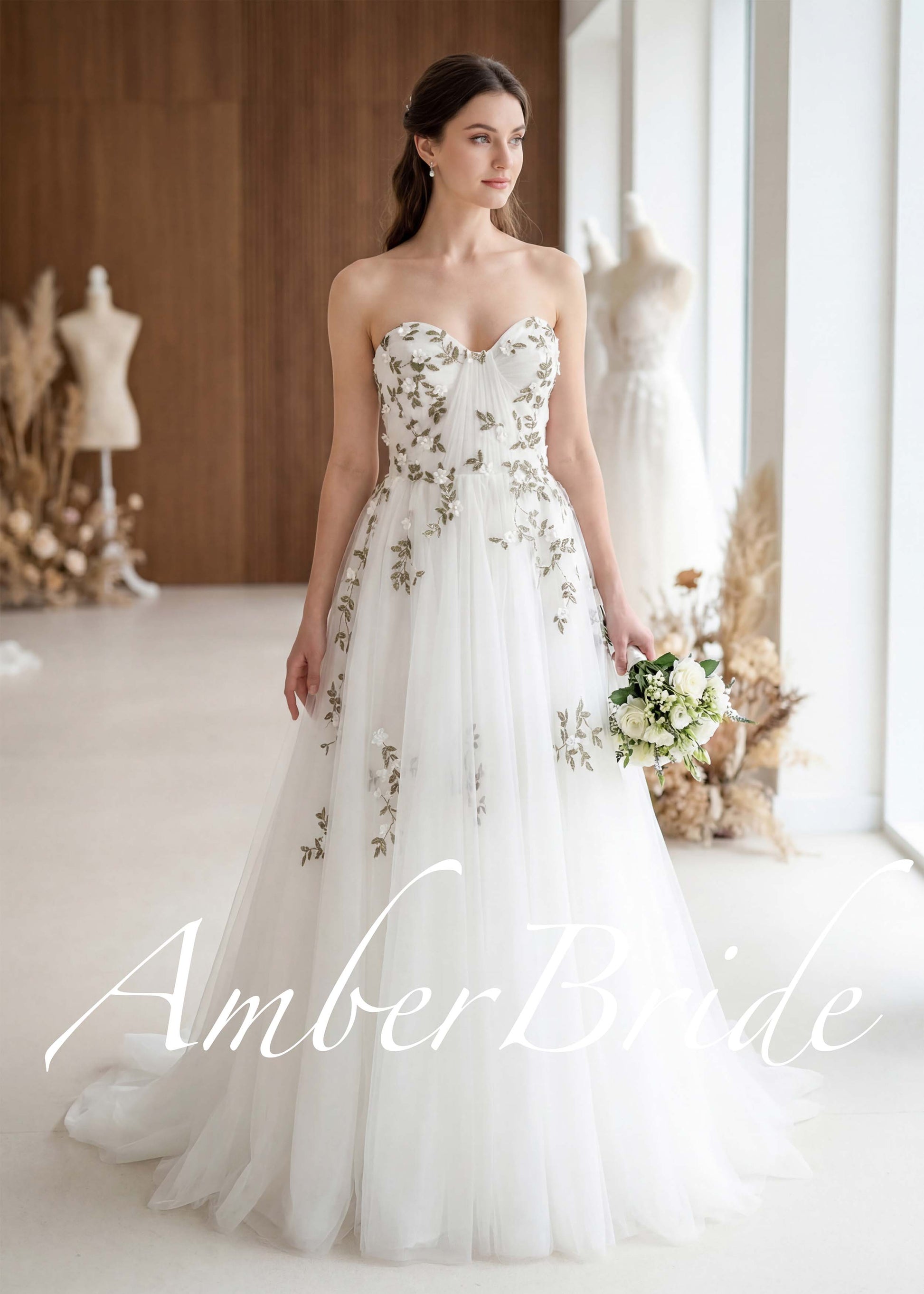 Strapless A-line wedding dress in white tulle with green floral embroidery and a sweetheart neckline.