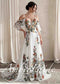 A-line wedding dress with floral embroidery, V-neck, and detachable flutter sleeves in white chiffon.