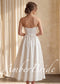 Back view of a white, tea-length satin bridal dress with a strapless bodice and lace-up corset back.