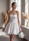 White satin mini dress with a strapless corset-style bodice and a puffy, gathered skirt.