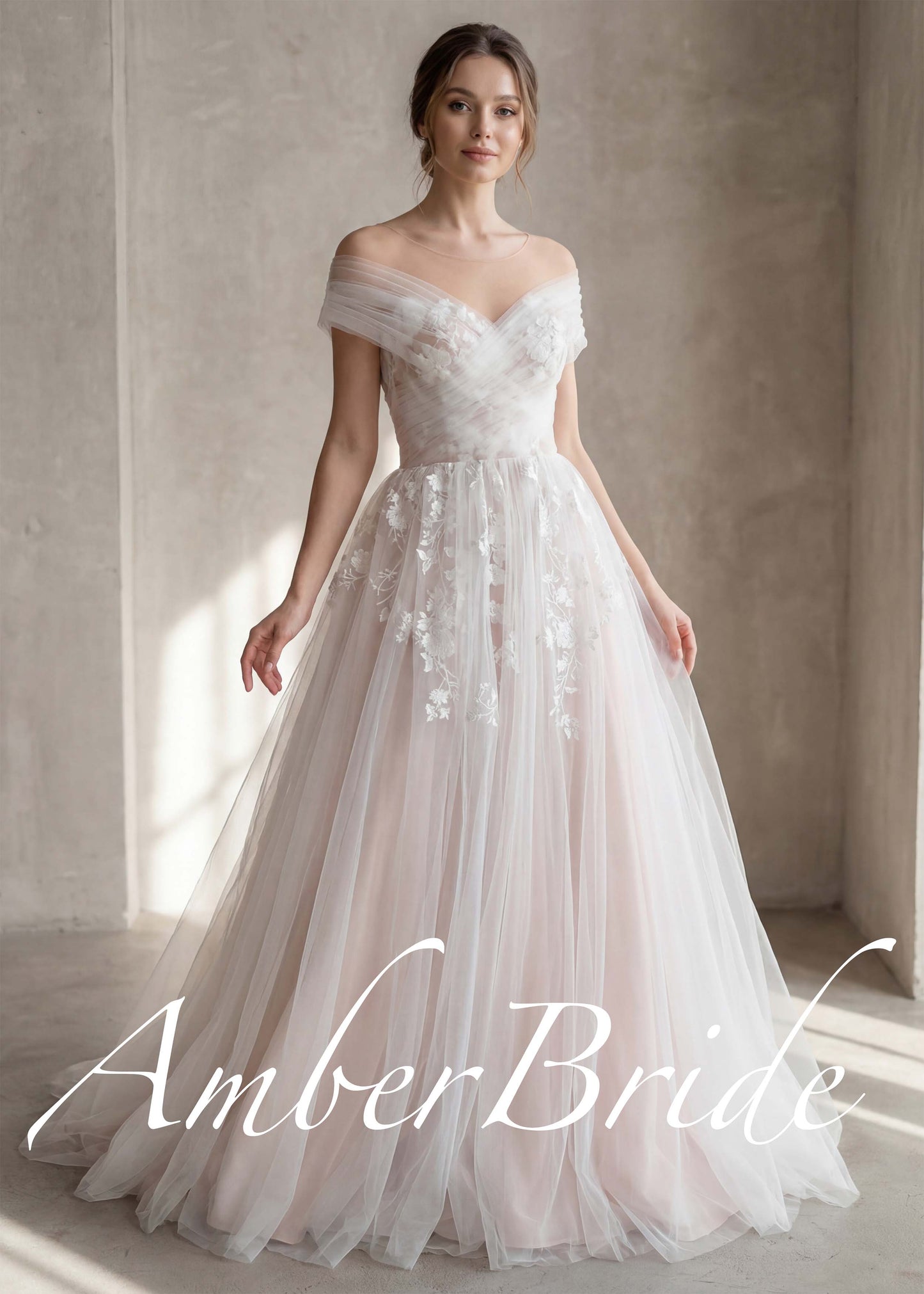 Off-shoulder tulle wedding dress with illusion neckline and delicate white floral appliqué on a blush-toned skirt.