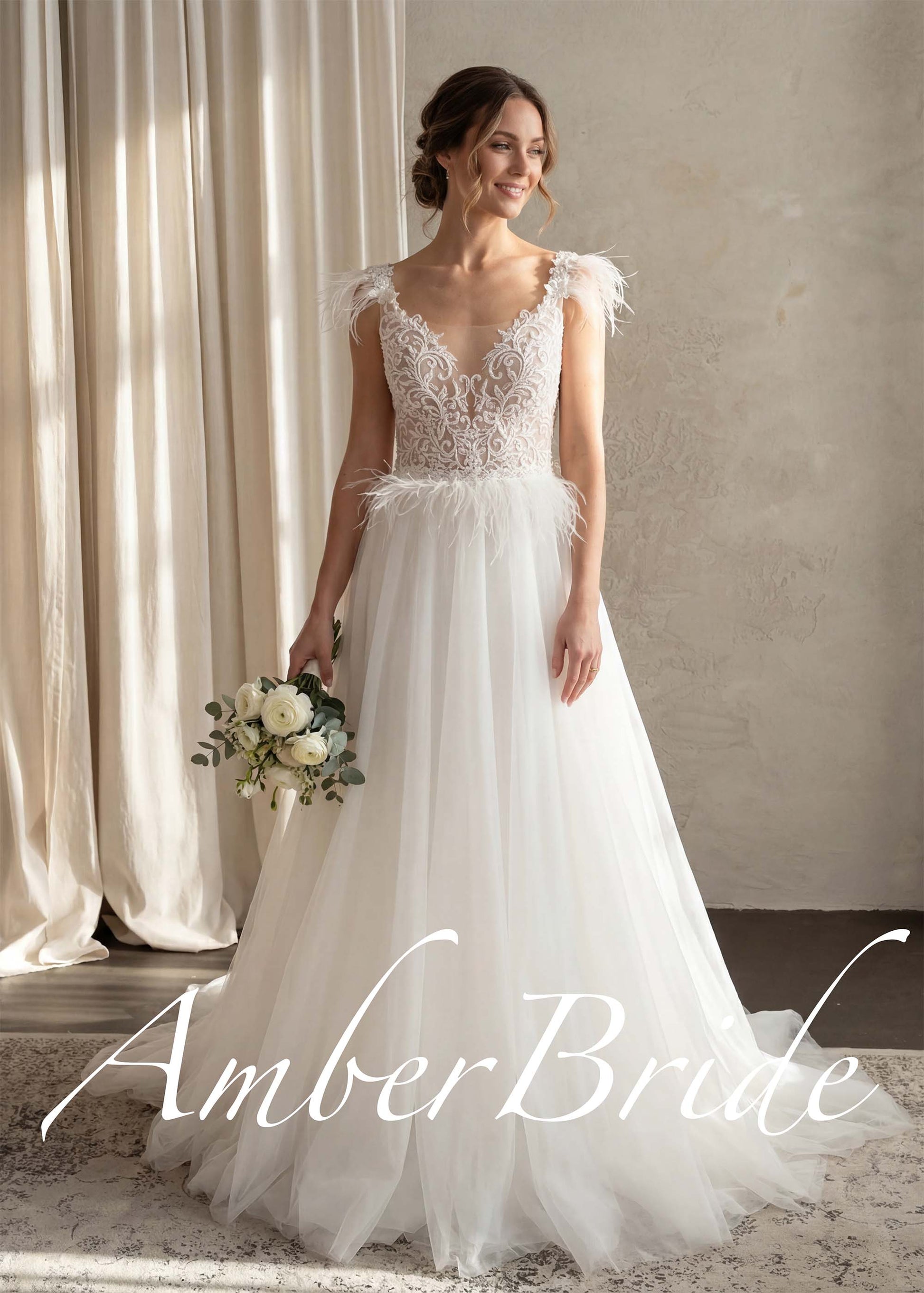 White A-line wedding dress with a sheer lace bodice, feather-adorned straps, feather waist detail, and tulle skirt.