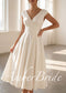 Ivory tea-length satin A-line dress with a V-neck, cap sleeves, and a fitted waistband.