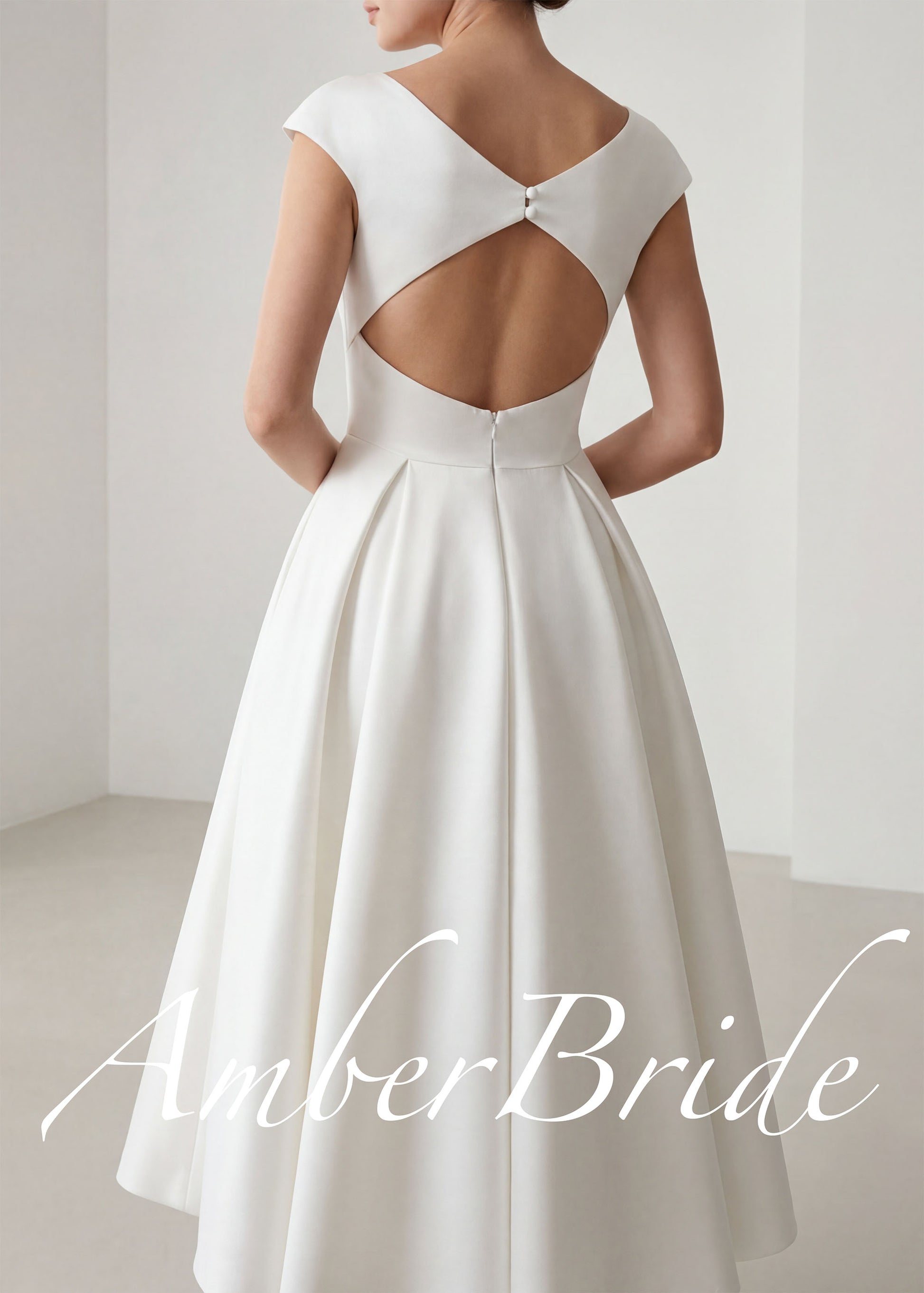 Back view of a white satin tea-length A-line bridal dress with cap sleeves and a cut-out open back with buttons.