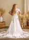 White A-line wedding dress with flutter sleeves, open back, and colorful floral embroidery on the skirt and train.