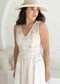Woman wearing a white lace dress and beige hat against a white background