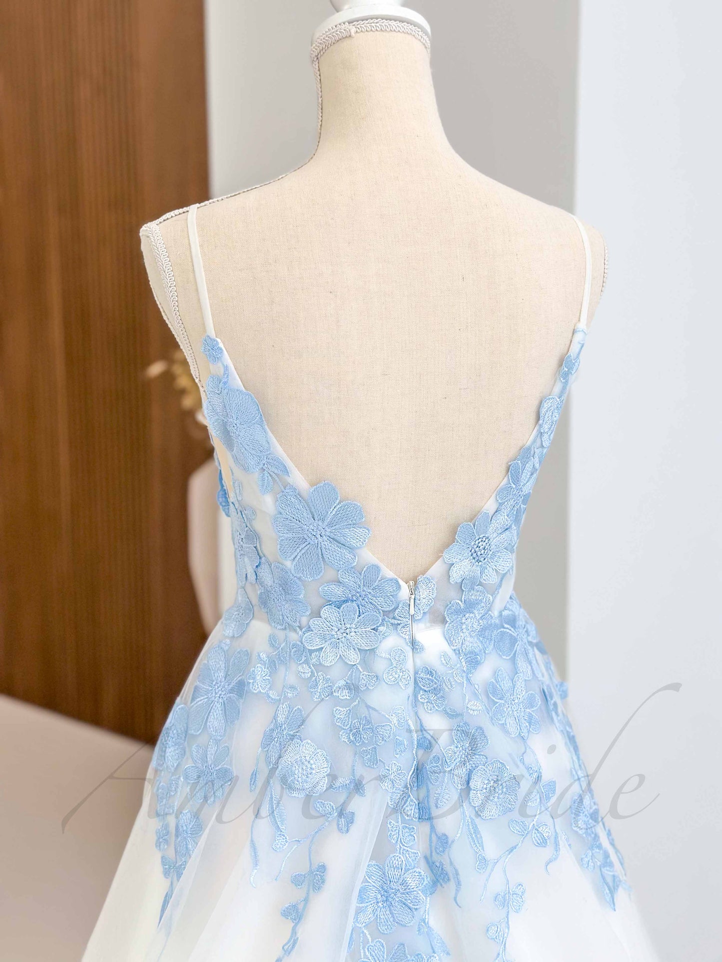 Back view of a sky blue floral tulle wedding dress with spaghetti straps, open back, and intricate blue embroidery.