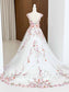Backless A-line wedding dress in white tulle with pink floral embroidery and a button-up back on a mannequin.