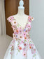 A-line tulle wedding dress with a deep V-neck, cap sleeves, and colorful floral embroidery on a white background.