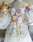 White A-line bridal dress with colorful floral embroidery, sweetheart neckline, and detachable sheer puffy sleeves.