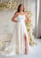 White strapless A-line wedding dress featuring a ruched bodice and a high thigh slit in flowy chiffon fabric.