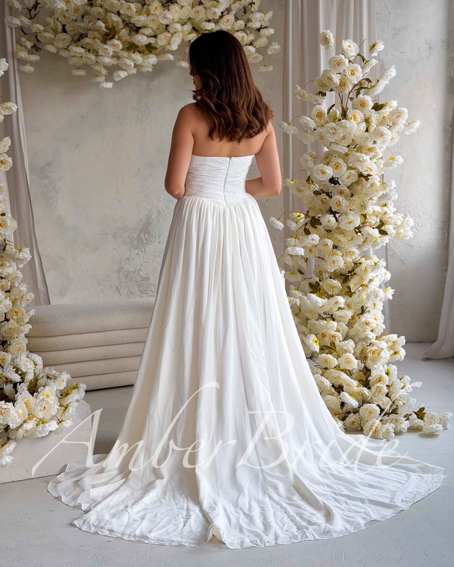 Back view of a white strapless A-line chiffon wedding dress featuring a ruched bodice and floor-length skirt.