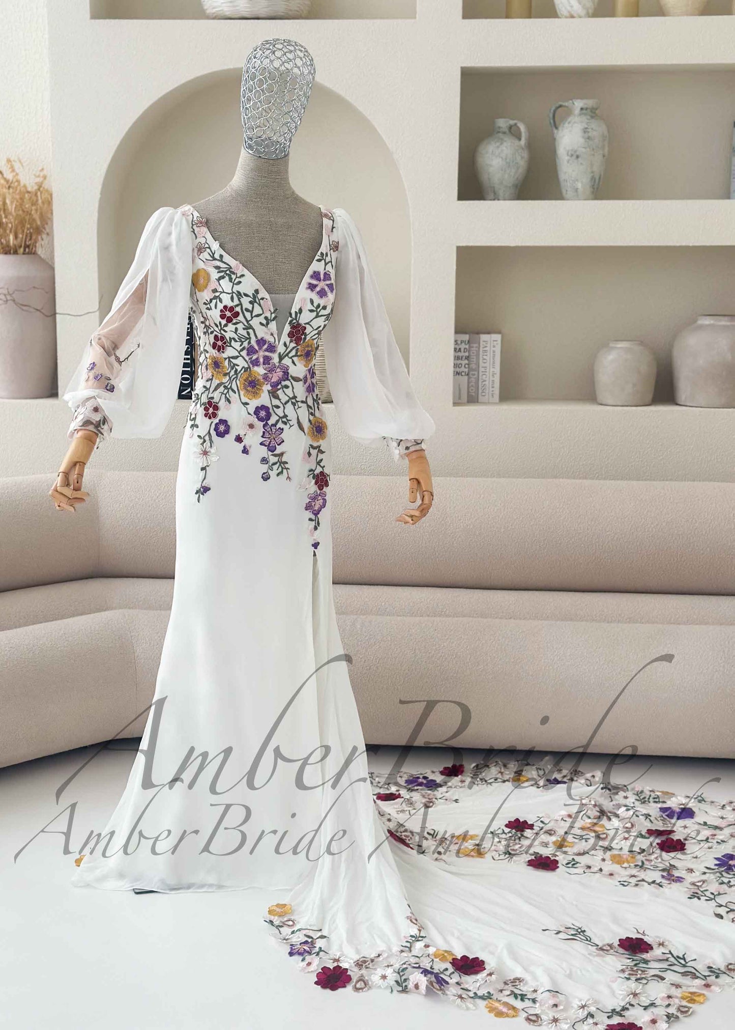 White mermaid dress with deep V-neck, sheer puff sleeves, and colorful floral embroidery on bodice and long train.