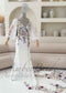 White mermaid dress with deep V-neck, sheer puff sleeves, and colorful floral embroidery on bodice and long train.