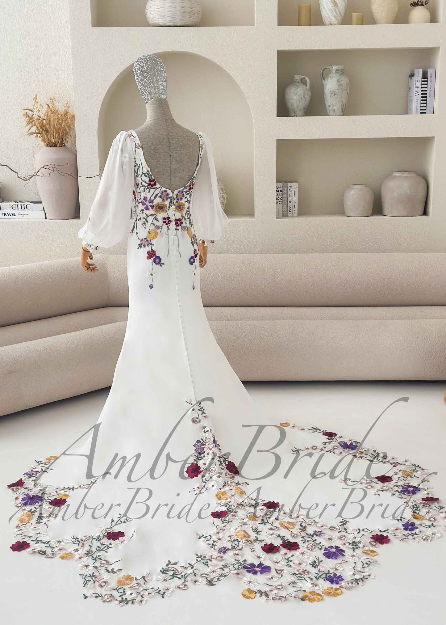 White mermaid bridal gown with sheer puff sleeves, scoop back, and colorful floral embroidery on bodice and train.