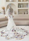 White mermaid bridal gown with sheer puff sleeves, scoop back, and colorful floral embroidery on bodice and train.