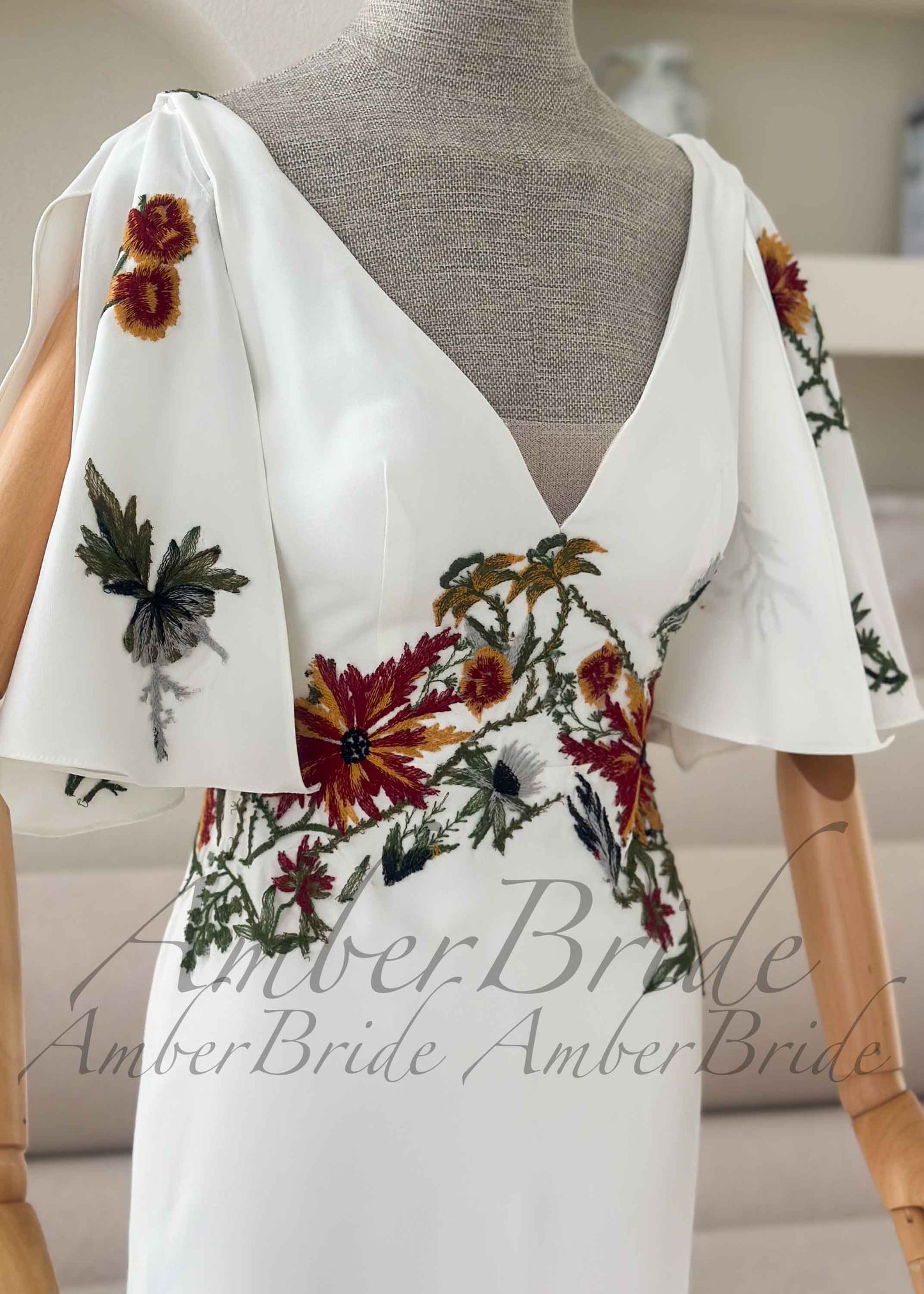 Ivory crepe mermaid dress with V-neck, detachable flutter sleeves, and earthy floral embroidery at bodice and sleeves.