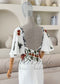 White crepe mermaid dress with a deep back, floral embroidery, and detachable flutter sleeves on a mannequin.