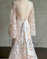 Back view of boho wedding dress with white floral embroidery, cape sleeves, open back, and a white waist tie ribbon.
