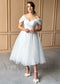 White tea-length glitter tulle wedding dress with off-shoulder sleeves, sweetheart corset bodice, and full skirt.