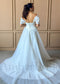 White A-line organza wedding dress with off-shoulder sleeves, corset back, and a full, flowing skirt.