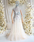 Nude A-line wedding dress with a square neckline, floral pastel embroidery, and a flowing tulle skirt on a mannequin.