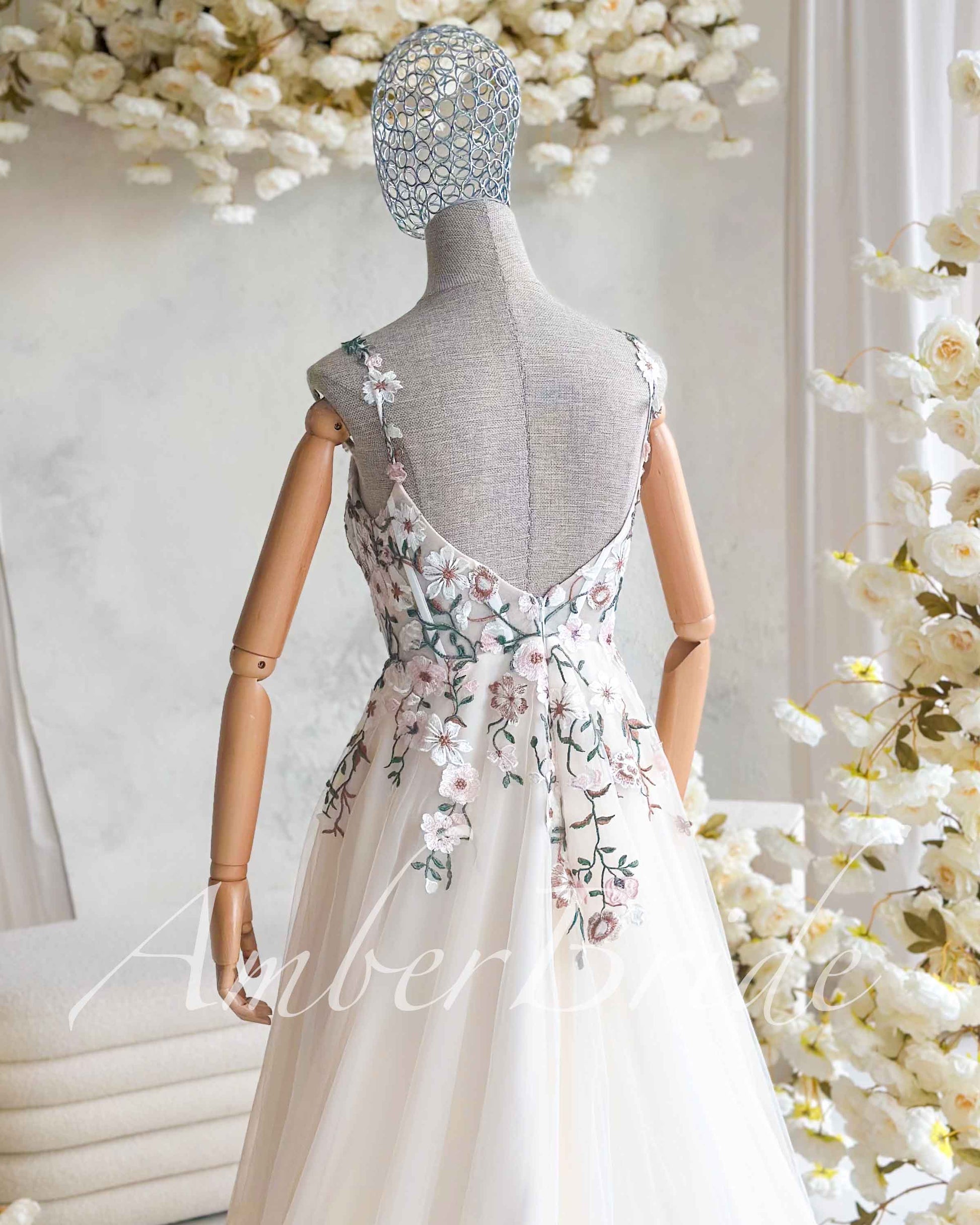 Nude A-line wedding dress with open back, square neckline, and delicate pastel floral embroidery on tulle.