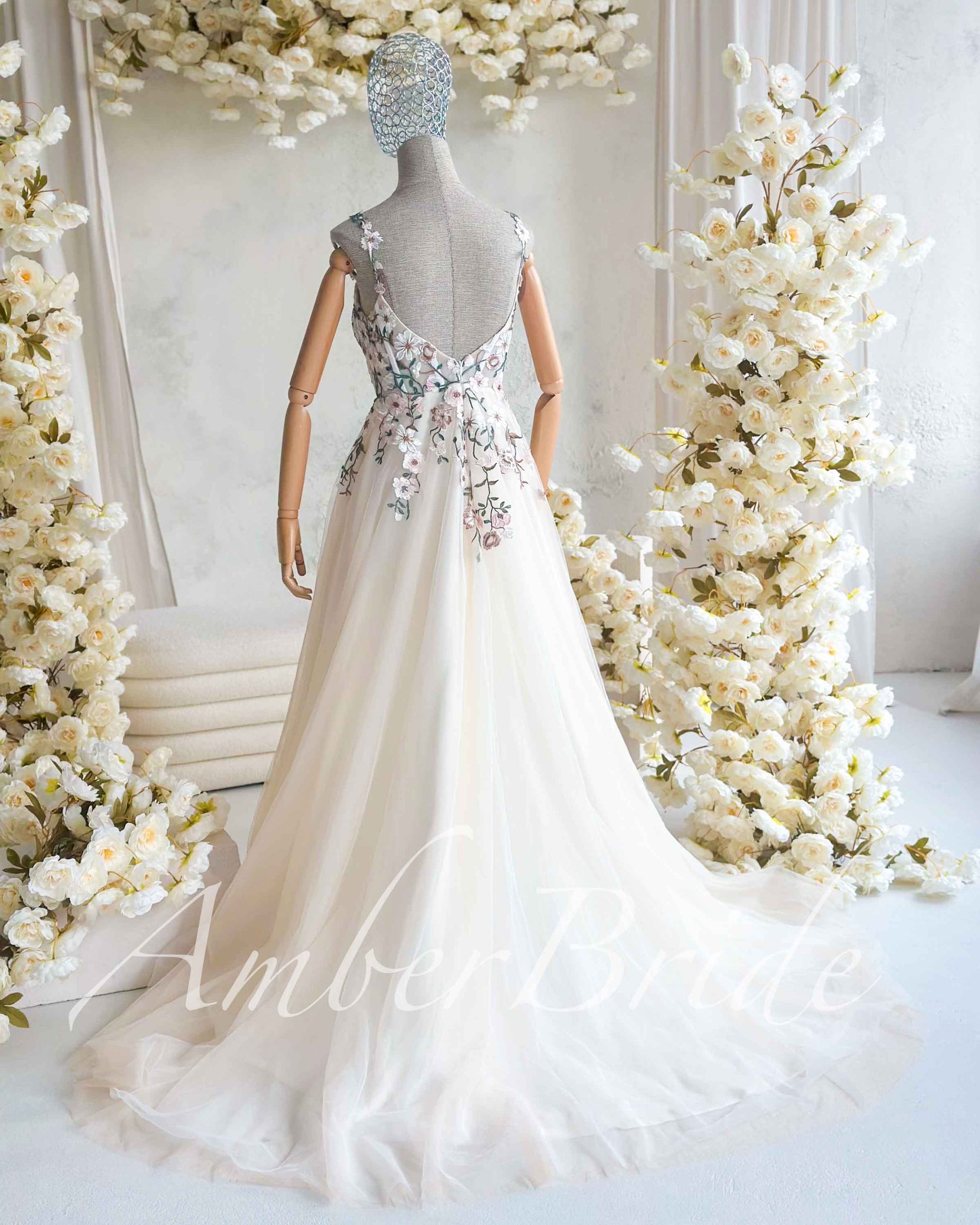 Nude A-line wedding dress with open back, square neckline, and pastel floral embroidery on tulle fabric.