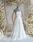 White strapless A-line wedding dress with a ruched bodice and flowing chiffon skirt on a mannequin.