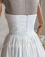 White strapless wedding dress on a mannequin featuring a ruched chiffon bodice and a center back zipper closure.