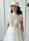 A bride wears a boho A-line dress with a white lace high-neck bodice, short sleeves, and a soft tulle skirt.