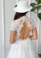 Back view of a boho tulle wedding dress with a sheer lace back, keyhole cutout, pearl buttons, and short sleeves.