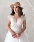 Bohemian wedding dress with V-neck, cap sleeves, illusion lace bodice, and tulle skirt, worn with a tan felt hat.