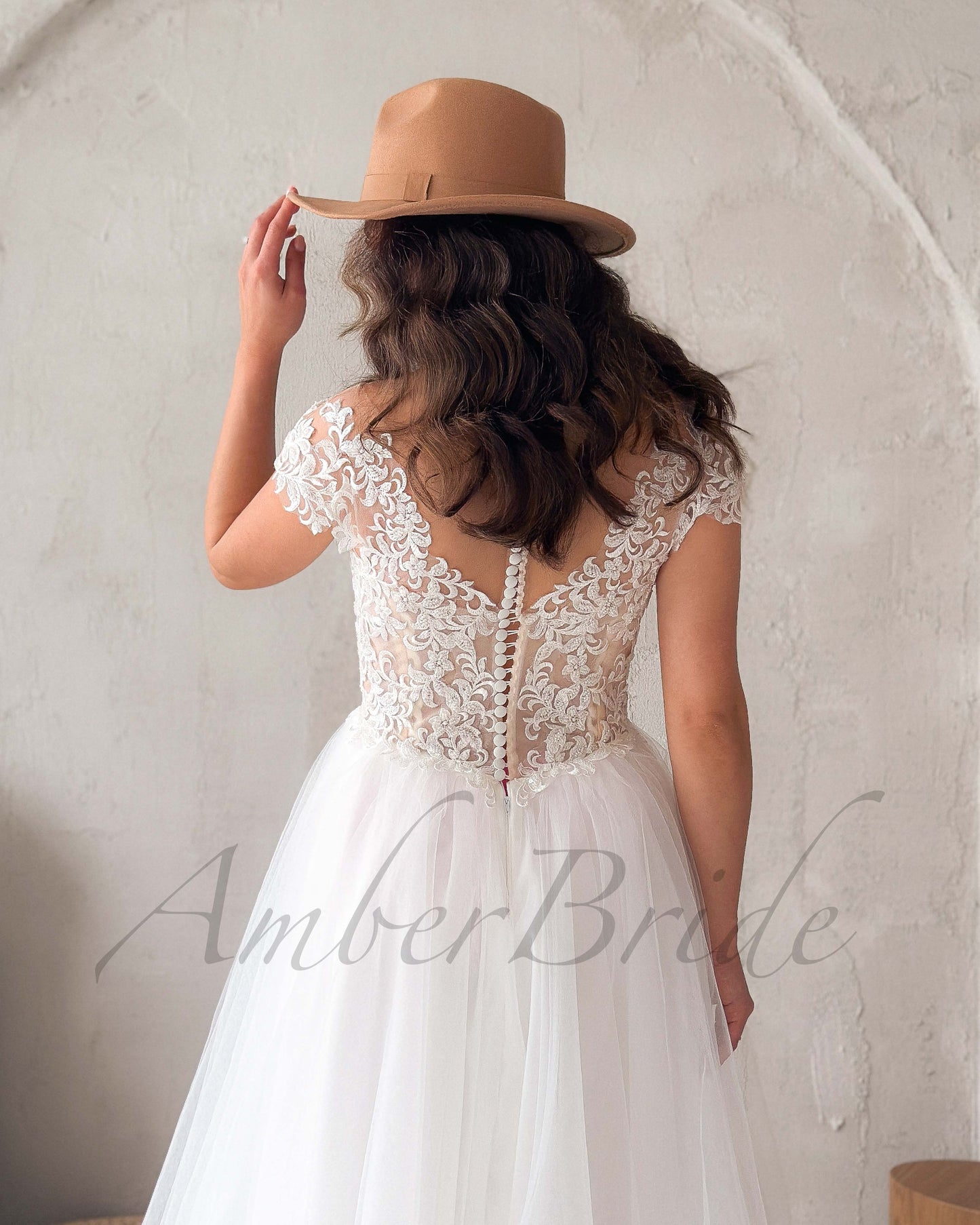 Back view of a bohemian wedding dress featuring an illusion lace back, cap sleeves, and a row of buttons.