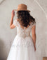 Back view of a bohemian wedding dress featuring an illusion lace back, cap sleeves, and a row of buttons.