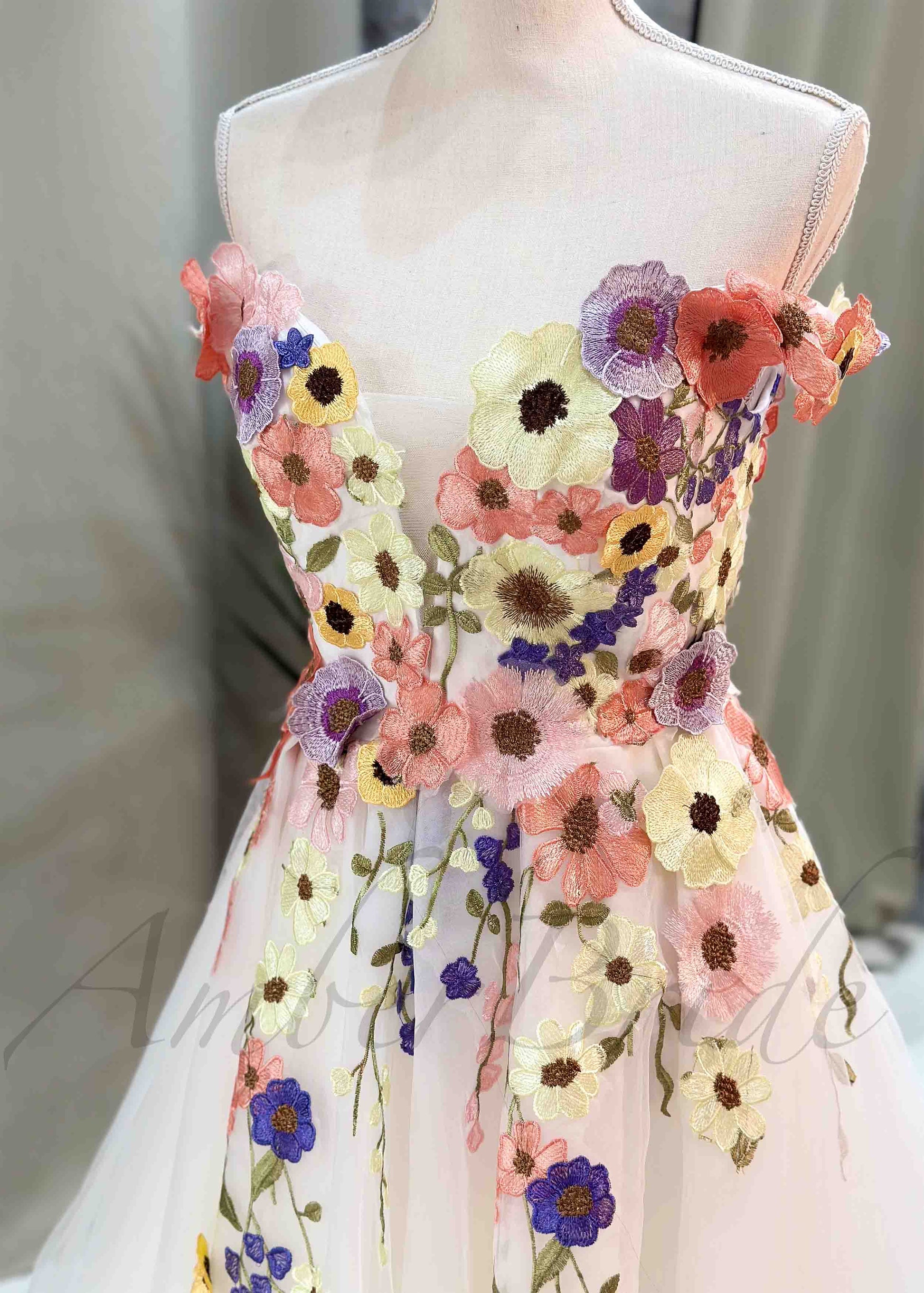 Off-shoulder A-line wedding dress featuring colorful 3D floral embroidery on a white tulle bodice.