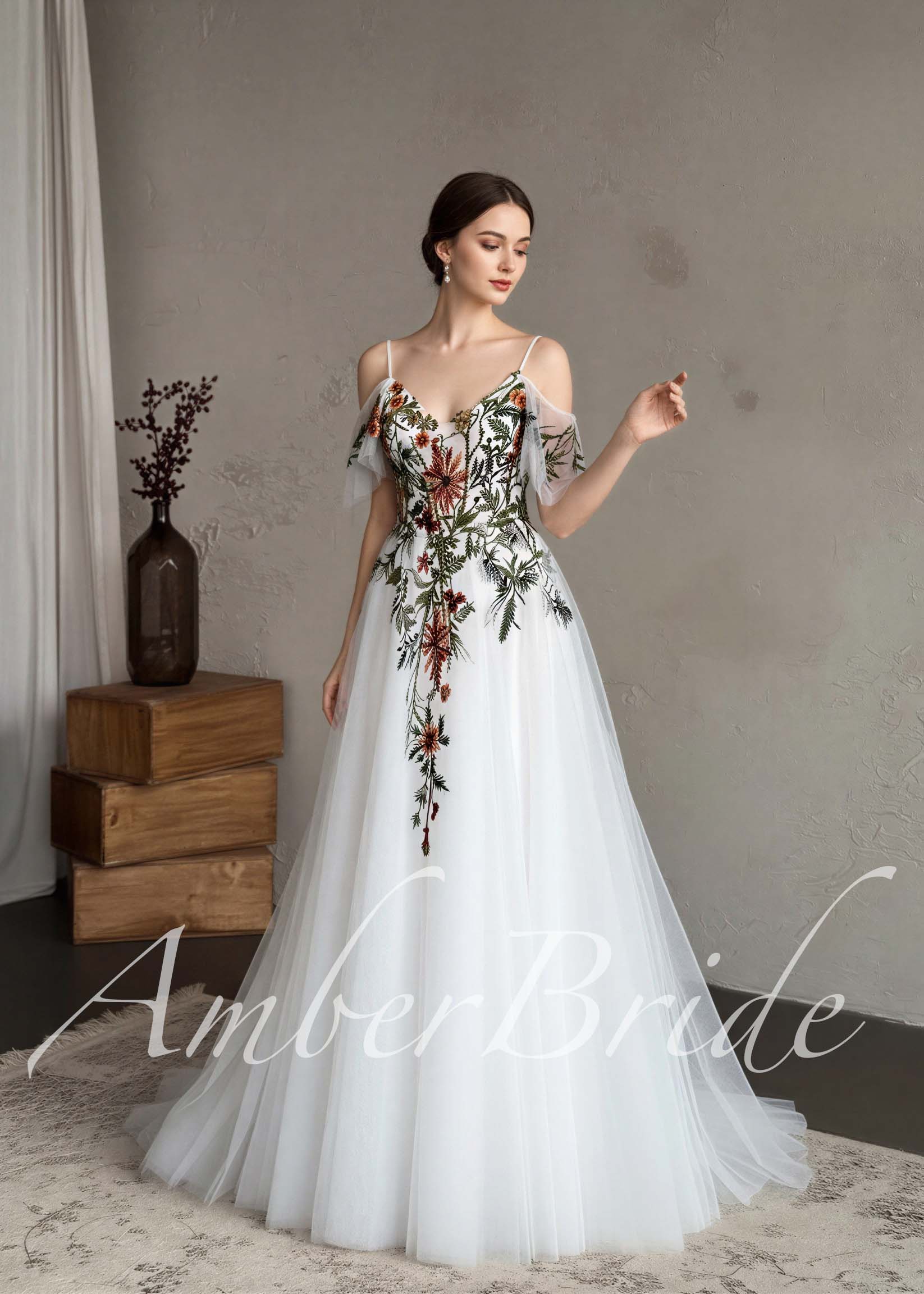 A-line white tulle wedding dress with spaghetti straps, flutter sleeves, and vibrant floral embroidery on the bodice.