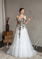 A-line white tulle wedding dress with spaghetti straps, flutter sleeves, and vibrant floral embroidery on the bodice.