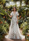 A-line wedding dress with a deep V-neck, flutter sleeves, and colorful floral embroidery on white chiffon.