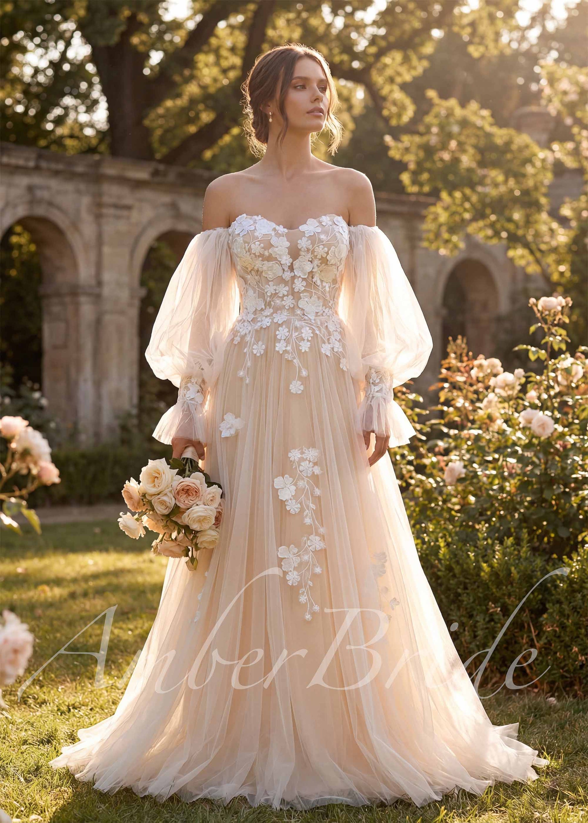 Off-the-shoulder A-line wedding dress in nude tulle with white floral lace appliques and sheer puff sleeves.