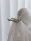 Sheer white tulle wedding veil attached to a silver metal hair comb on a mannequin head.
