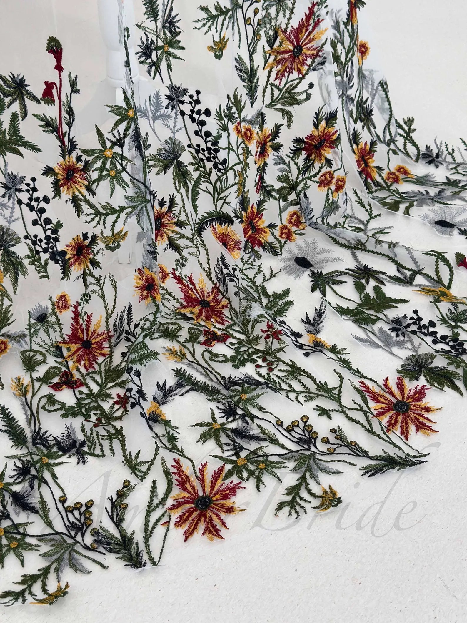 White tulle veil featuring intricate, colorful floral and foliage embroidery in shades of red, yellow, and green.