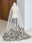 White tulle bridal veil on a mannequin featuring colorful, detailed floral embroidery along the hem.